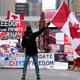 A protester waves a Canadian flag in front of parked vehicles on Rideau Street at a protest against COVID-19 measures that has grown into a broader anti-government protest, in Ottawa, Ontario, Friday, Feb. 11, 2022.